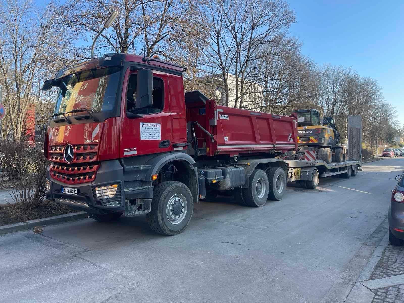 Firmeneigener Tieflader mit Bagger auf dem Weg zur Baustelle